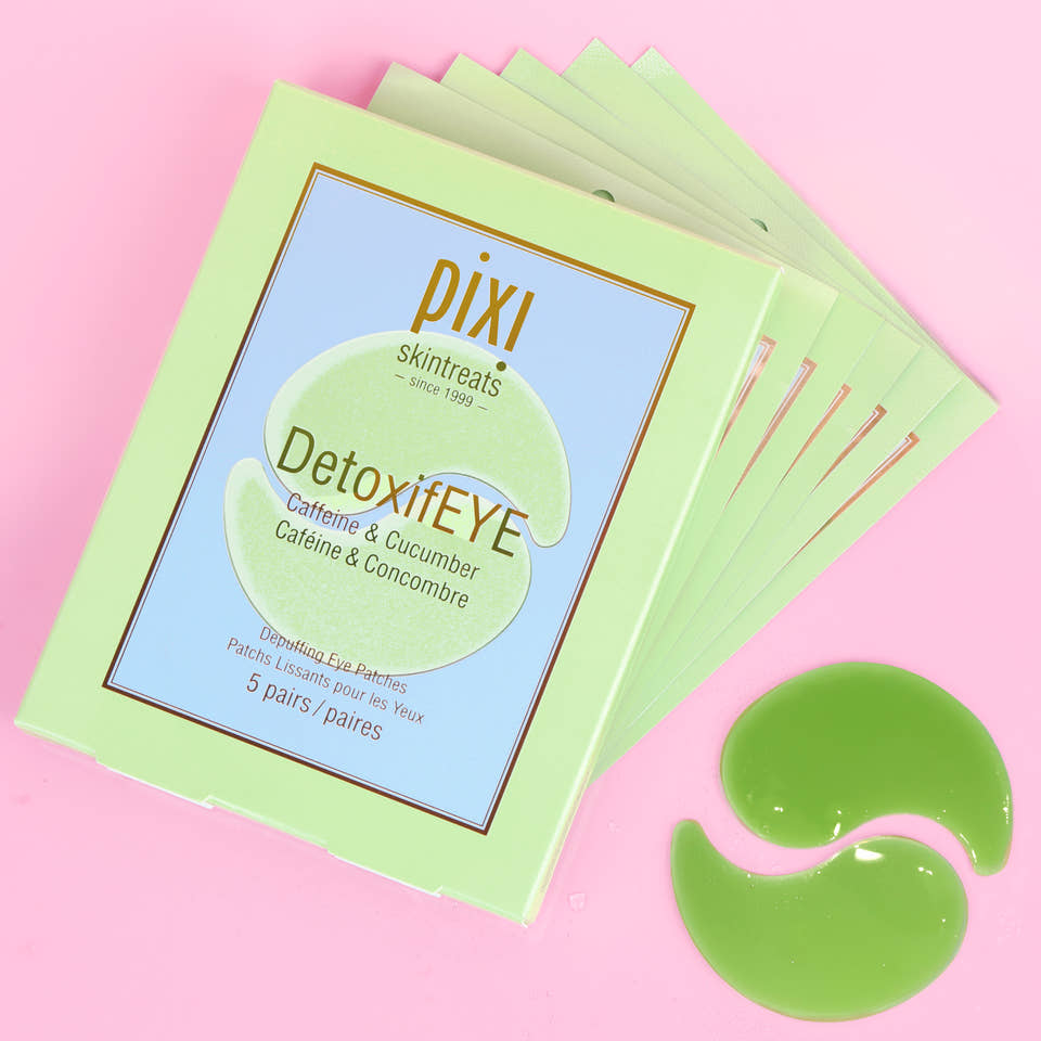 A 5-pack stack of Pixi Skintreats DetoxiEYE eye gel patches in a light green box, displayed on a pink background with two green gel patches placed in front. view 1