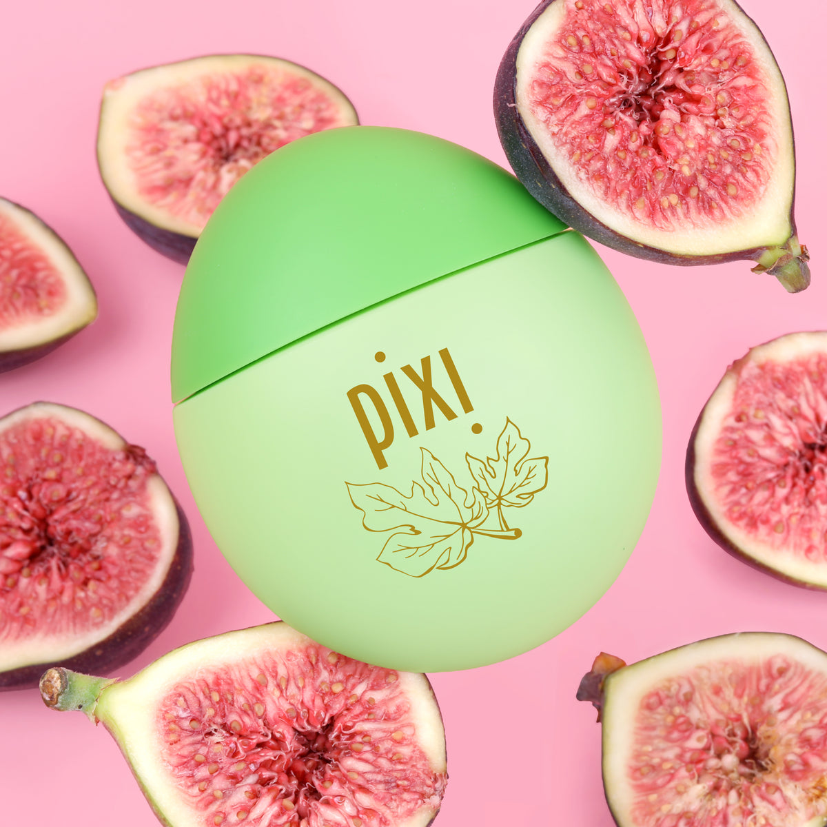 Pixi HandHero hand lotion including gold foil branding, surrounded by fresh sliced figs on a solid pink background.